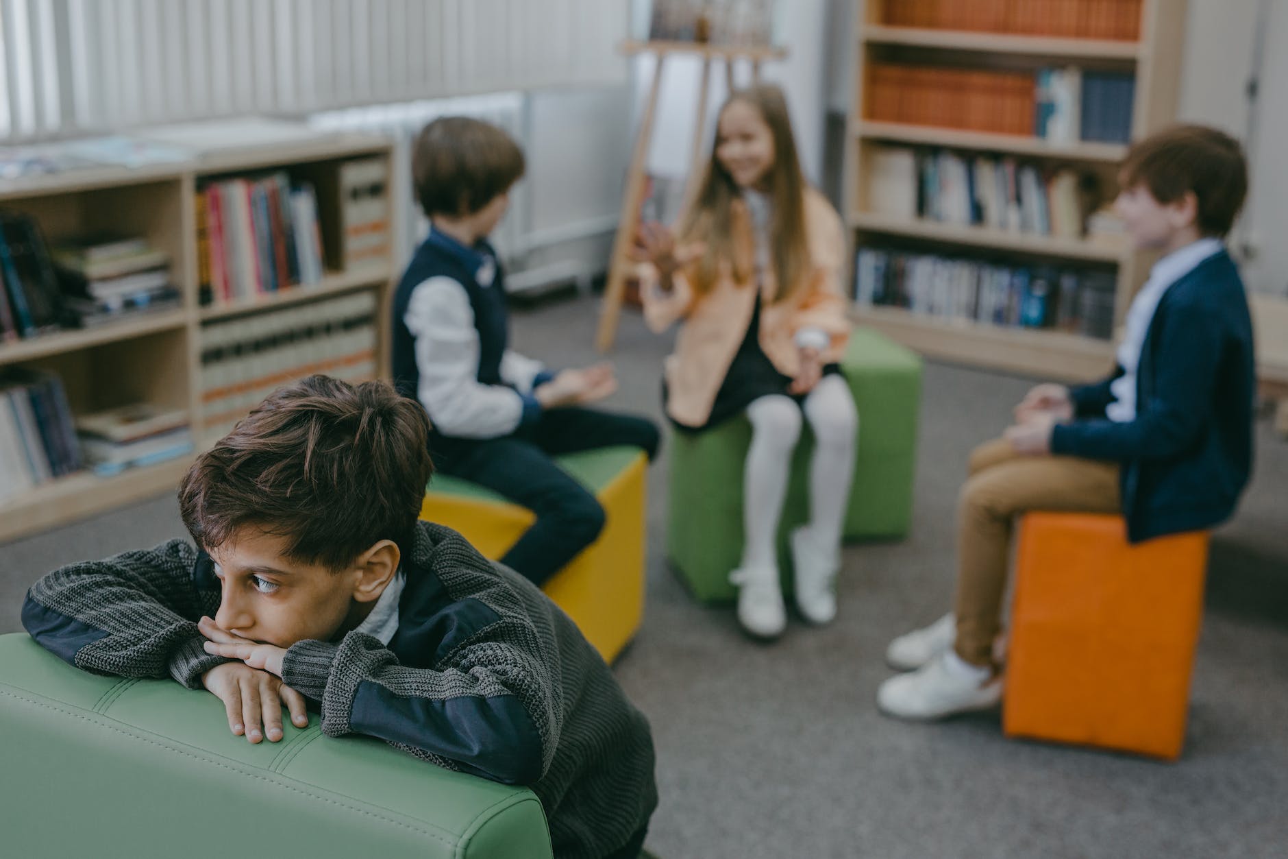 boy in gray sweater sitting on green leather couch in a library