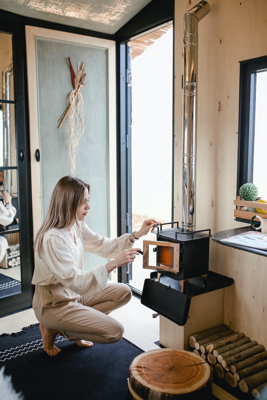 woman lighting a fire in the fireplace in a tiny house on wheels