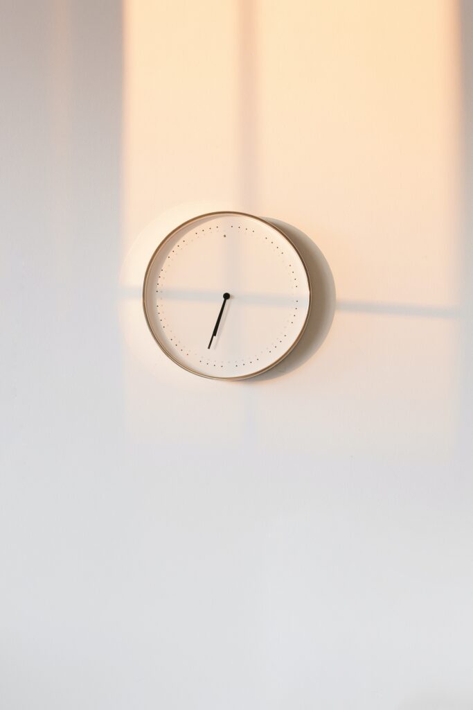 White wall with white clock symbolising minimalism