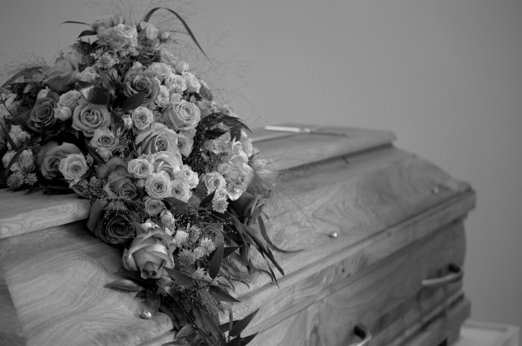 Black and white image with coffin and roses on top