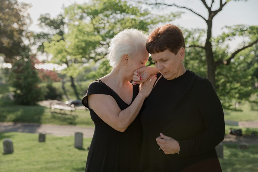 Two women, dressed in black, griefing. 