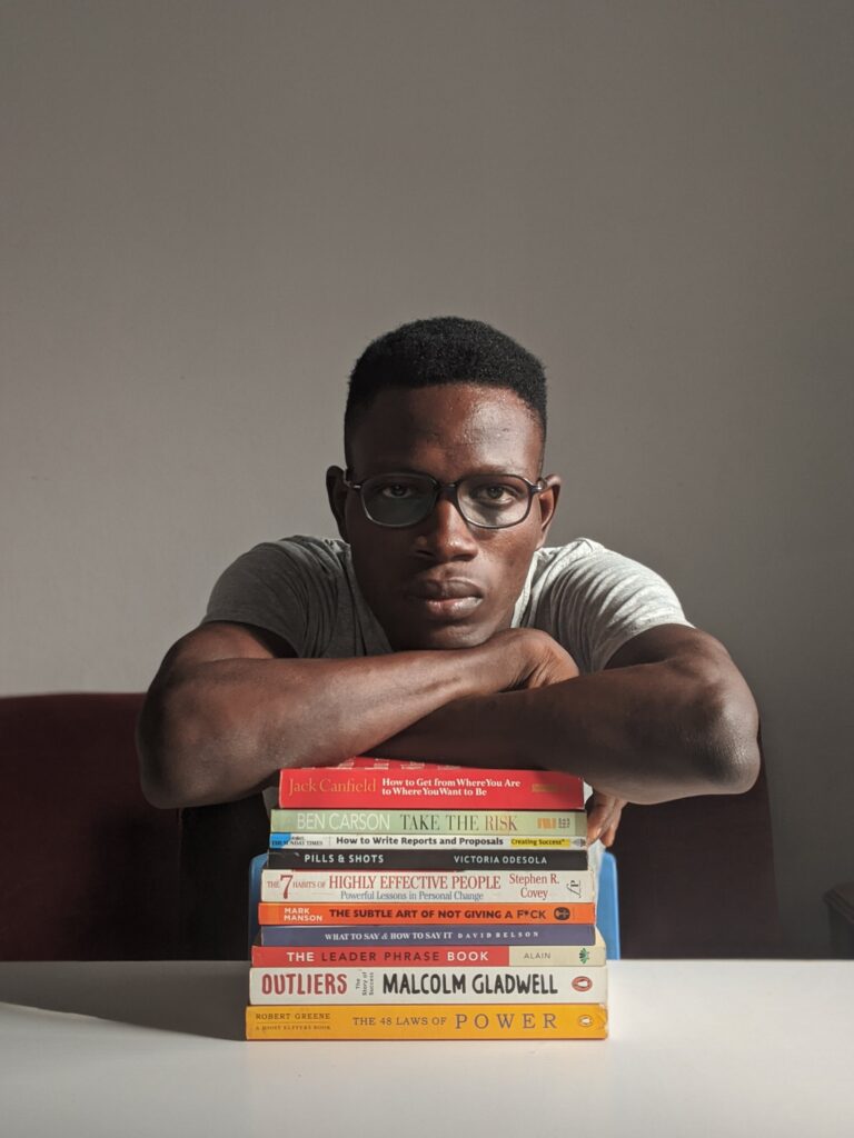 Young black man sitting behind a pile of books