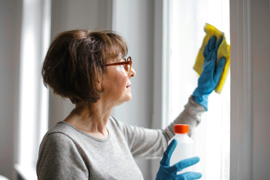Women with blue gloves cleaning a window