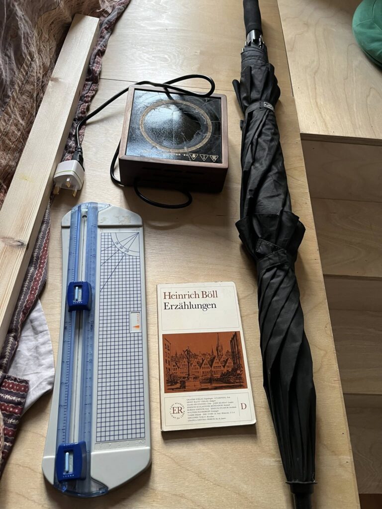 Black umbrella, book, hot plate, paper cutter, plank of wood