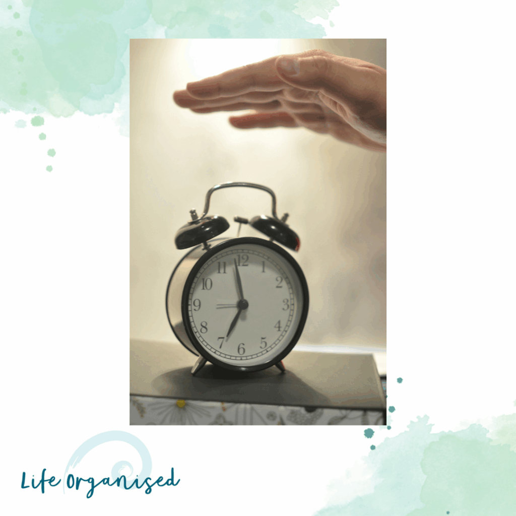 A person switiching off an old fashioned alarm clock