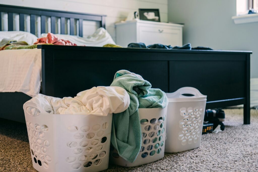 Black bed with three laundry baskets at the foot