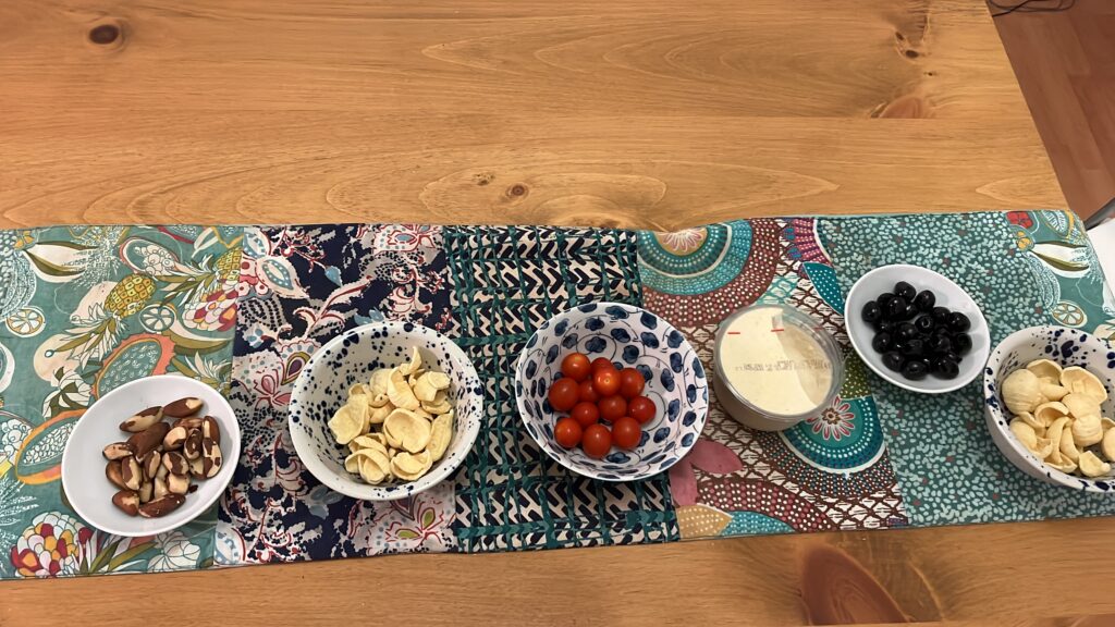 Wooden table with colourful runner and nibbles in bowls.